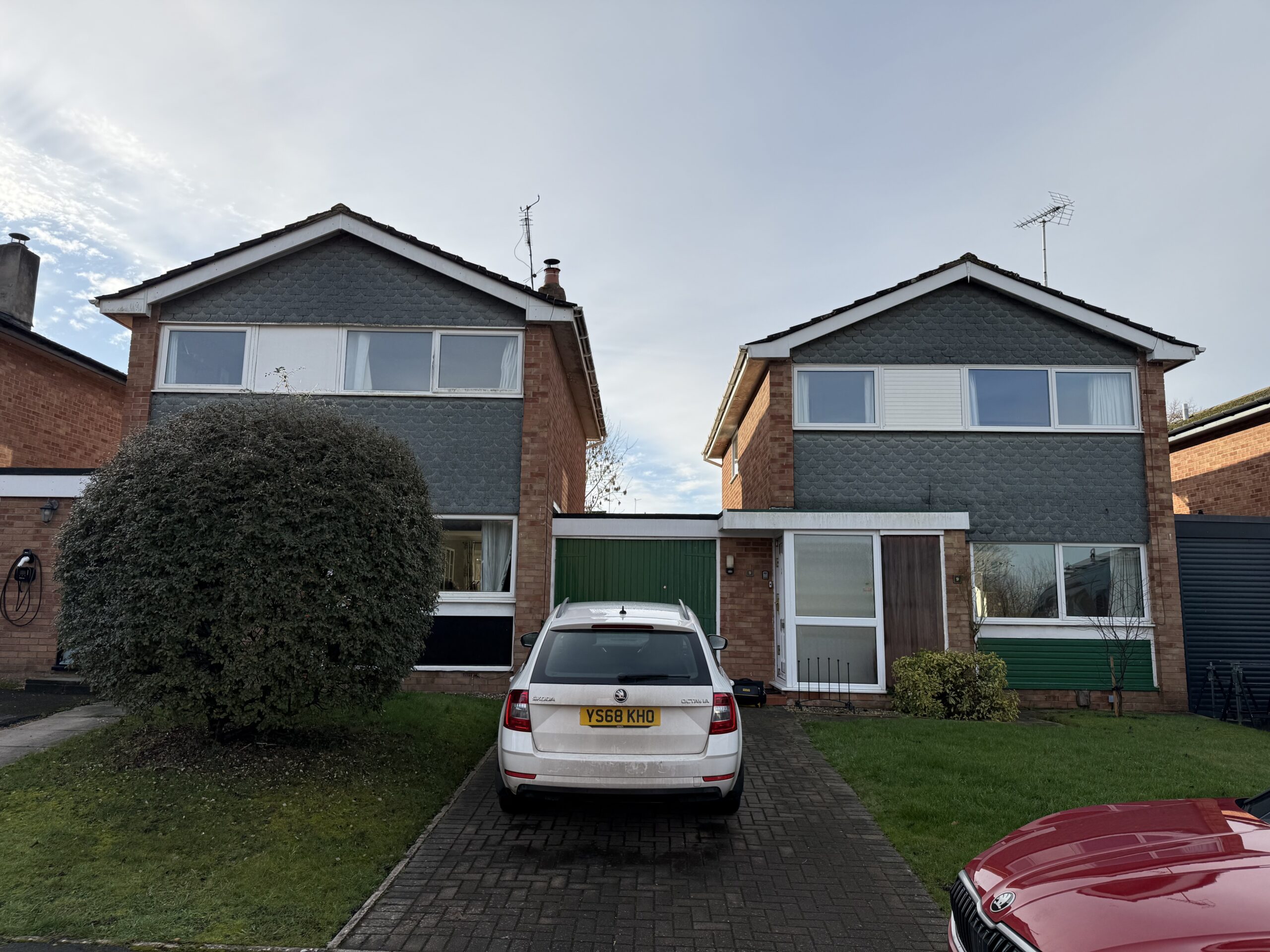 two houses with agrage attached to both and a car on drive